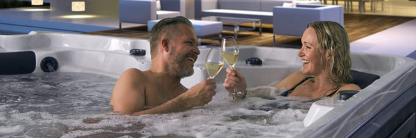 arcticspas man and woman drinking champagne in hot tub